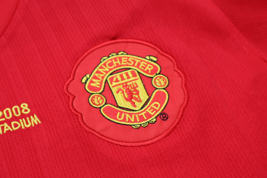 Primer plano del escudo bordado del Manchester United en el jersey retro 2008 de Cristiano Ronaldo, color rojo vivo.